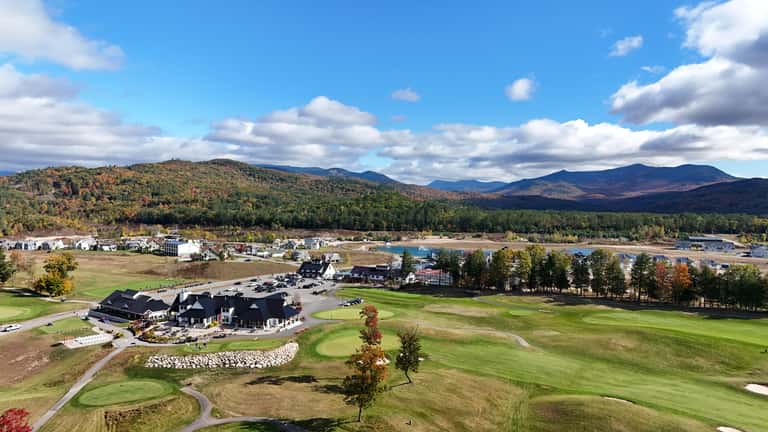 Aerial view of golf course clubhouse with mountain landscape in background