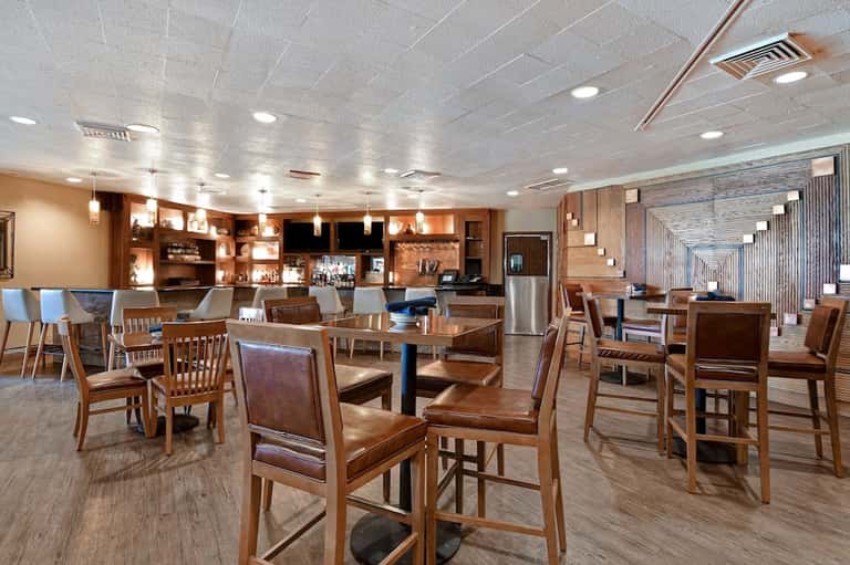 Hotel lobby restaurant with wooden chairs, tables, and illuminated shelving units