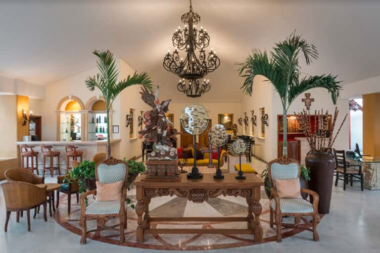 Elegant lobby with ornate chandelier, decorative sculptures, bar area, and classical furnishings