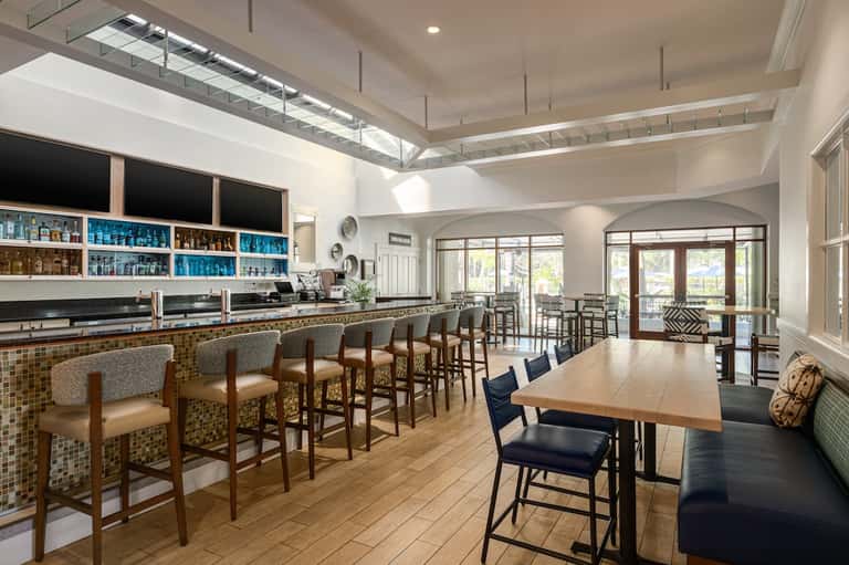 Hotel lounge bar with tiled counter, wooden seating, and glass doors to patio