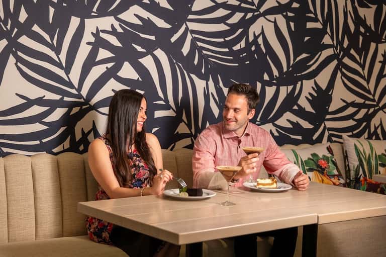 Couple dining at modern restaurant with dark botanical wall mural backdrop