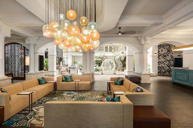 Elegant lobby with glass pendant chandeliers, tan seating, and geometric wall panels