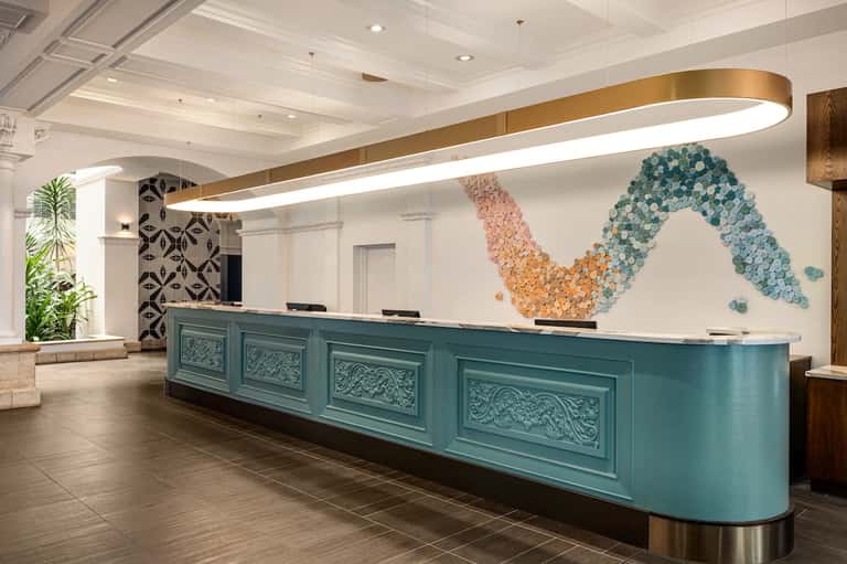 Hotel lobby reception desk with turquoise base and decorative wall art installation