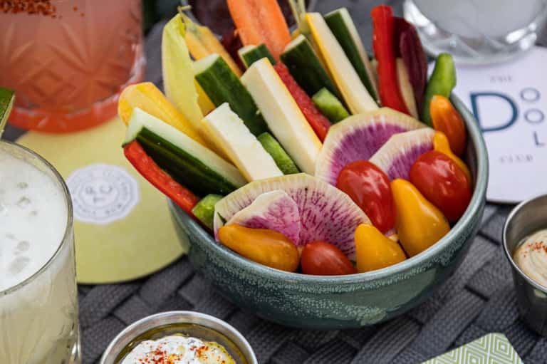 Gourmet appetizer platter with colorful fresh vegetables and creamy dips