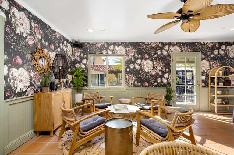 Botanical lounge with floral wallpaper, wooden furniture, and tropical plants