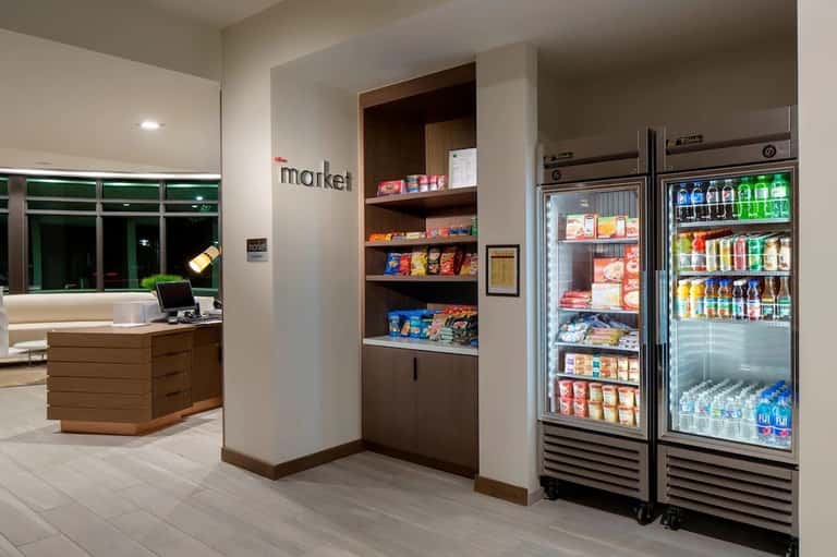 Hotel market area with checkout desk, shelving, snack displays, and refrigerated beverage coolers