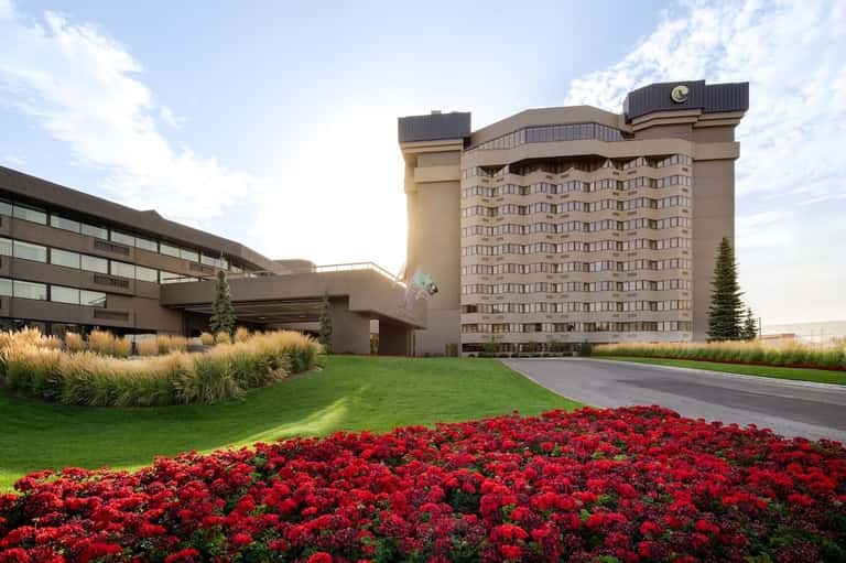 Modern hotel exterior with beige building, manicured red flower beds, and professional landscaping