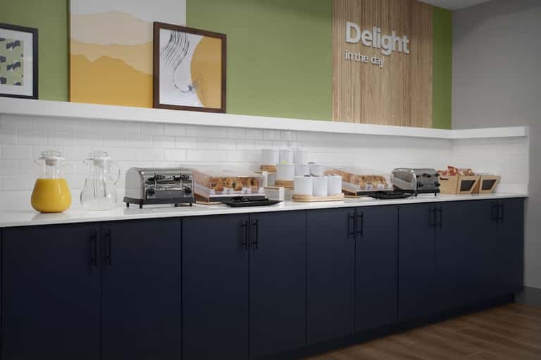 Breakfast buffet station with pastries, juice, and coffee service with green accent wall