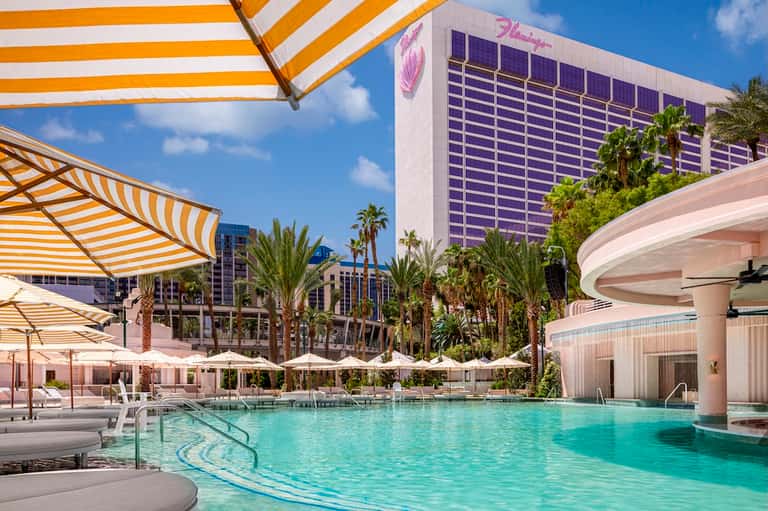 Luxury resort pool with white umbrellas, cabanas, and modern architecture with mountain views