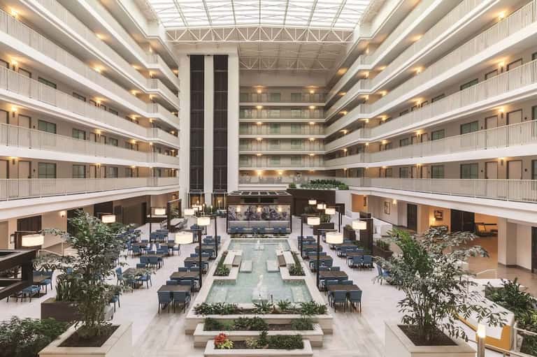 Modern hotel atrium lobby with multiple floors, central water feature, and contemporary furnishings