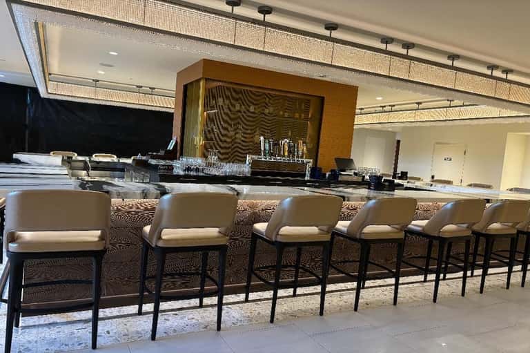 Hotel bar with cream leather seating, wooden accent wall, and ambient lighting