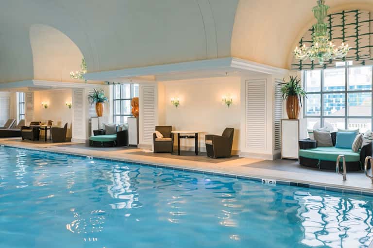 Indoor pool facility with arched ceiling, lounge seating, and natural lighting from windows