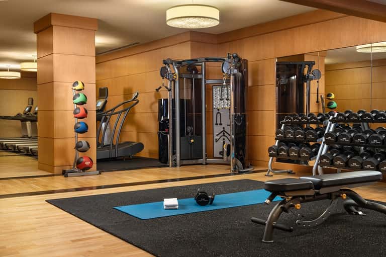 Modern fitness center with wood walls, exercise equipment, weights, and mirrors