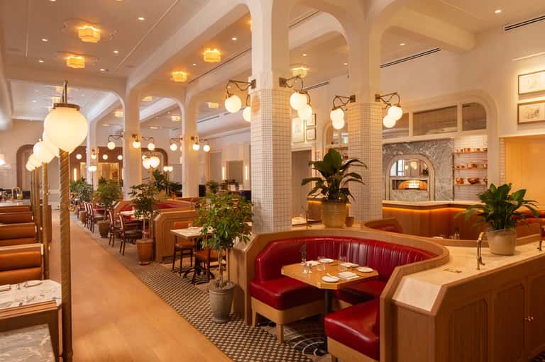 Elegant restaurant dining area with art deco design, globe lighting, red booths, and arched ceilings