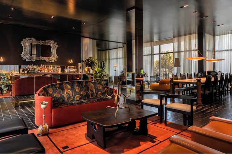 Luxury hotel lounge with red velvet sofa, bar area, and contemporary furniture in warm lighting