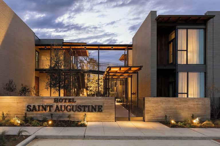 Hotel Saint Augustine modern entrance at dusk with brick facades, glass doors, and warm lighting