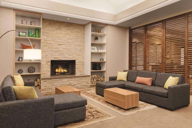 Contemporary living room with fireplace, built-in shelving, gray seating, and wood accents