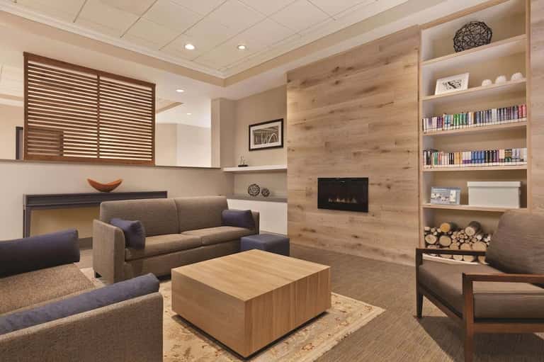 Contemporary hotel lounge with fireplace, built-in shelving, seating area, and wood accents