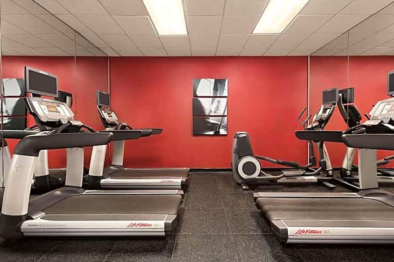 Fitness center with multiple treadmills, red accent walls, and cardio equipment