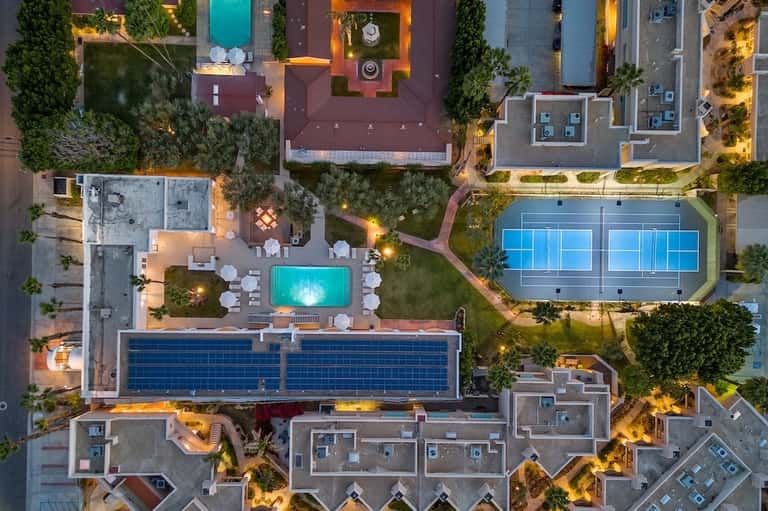 Aerial view of resort grounds showing multiple pools, tennis courts, and landscaping at dusk