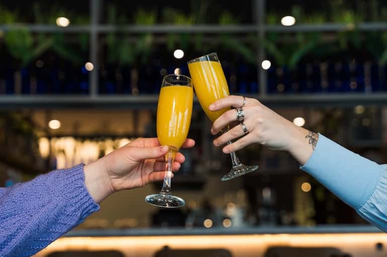 Two champagne flutes clinking together at evening rooftop bar celebration