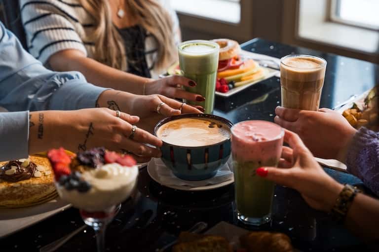 Friends enjoying beverages and food at casual resort cafe with ocean views and natural lighting