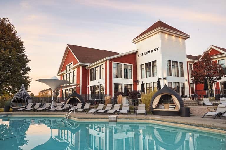 Modern resort with red building, white cabanas, and curved lounge chairs by pool
