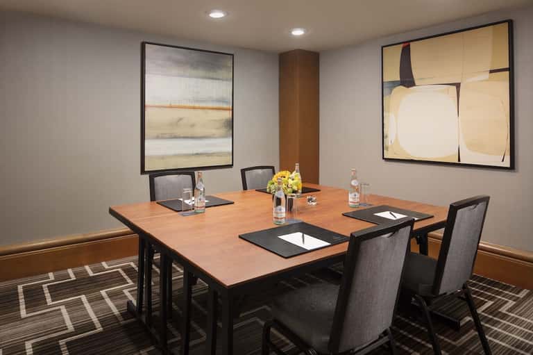 Professional meeting room with wooden table, gray chairs, and abstract wall art