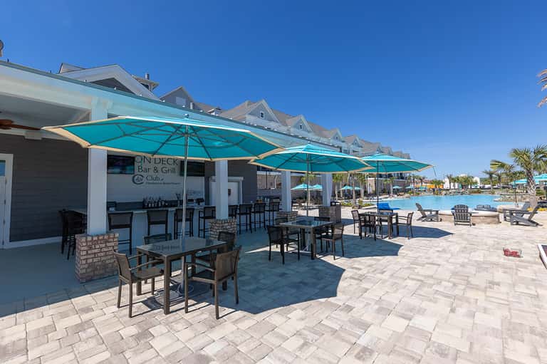 Beachfront bar and grill with turquoise umbrellas, patio seating, and ocean view