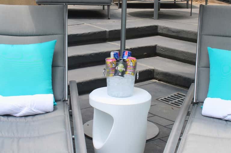 Luxury poolside cabanas with turquoise pillows, gray cushioning, and white side table