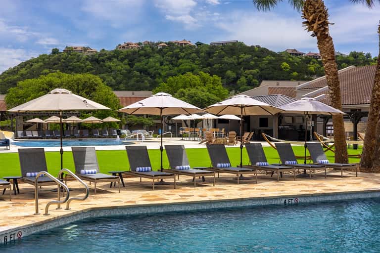 Luxury hilltop resort pool with umbrellas, lounge chairs, and scenic views of distant hills