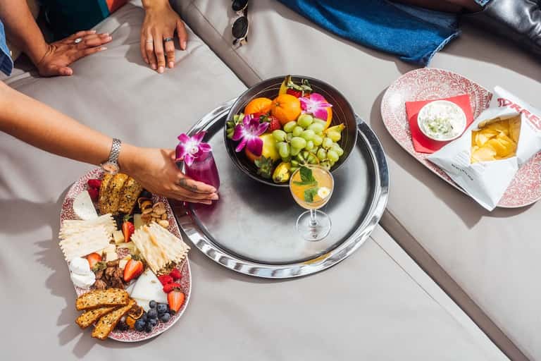 Overhead view of gourmet fruit platter and cocktail at upscale poolside dining table