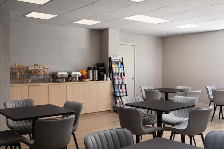 Bright spa lounge with wooden cabinetry, black tables, gray upholstered chairs, and product displays