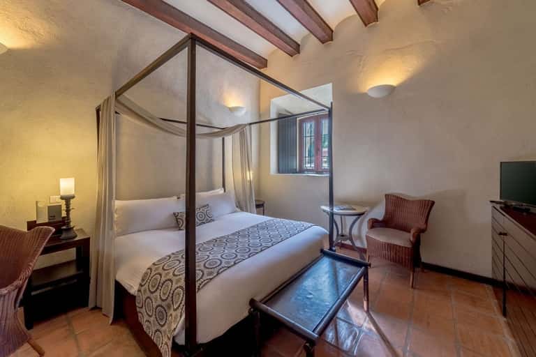 Elegant bedroom with four-poster canopy bed, exposed beams, and traditional decor