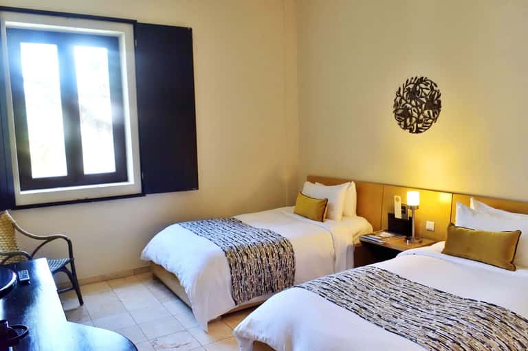 Hotel guest room with two beds, gold accents, and modern amenities with natural light