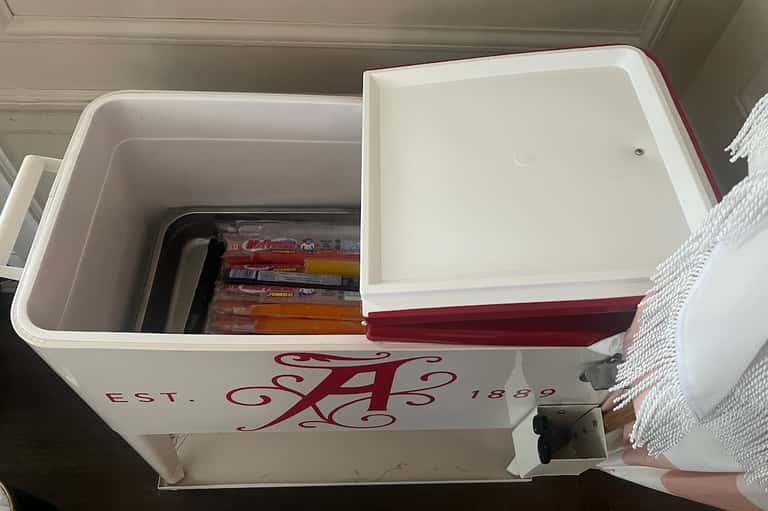 Open white cooler with red accents containing board games and beverages