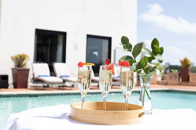 Champagne glasses with fruit garnish on poolside table overlooking resort pool