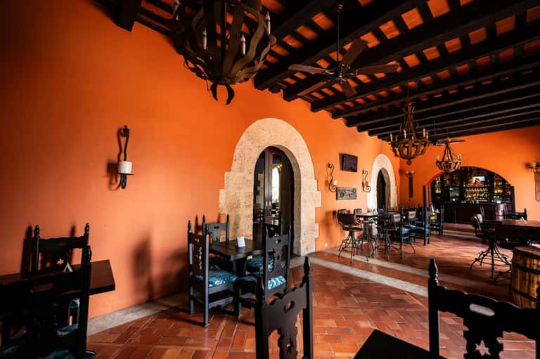 Spanish colonial-style restaurant interior with orange walls and decorative wooden beams