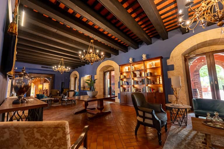 Grand hotel lobby with exposed wooden beams, chandeliers, archways, and elegant furniture arrangement