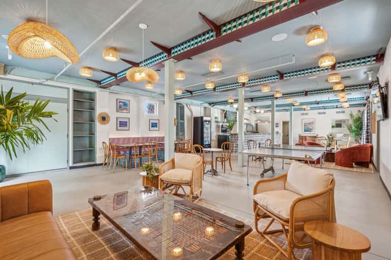 Bright lobby lounge with woven pendant lights, rattan chairs, and tropical plants