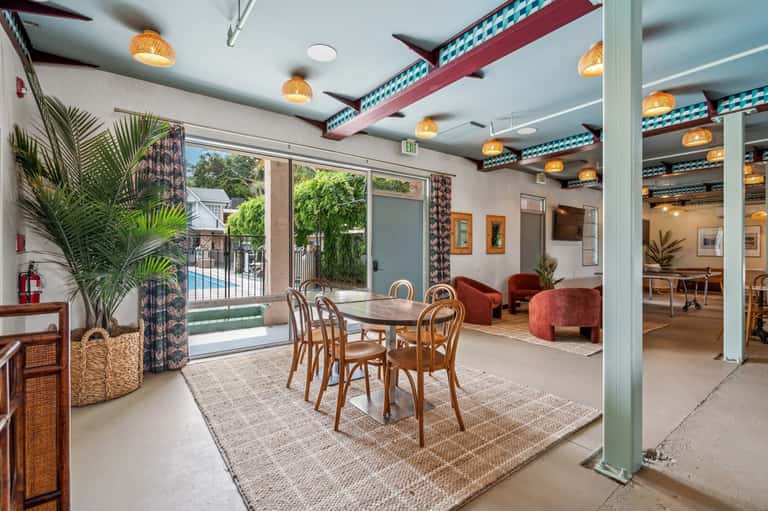Modern communal dining area with colorful ceiling beams and pool view access