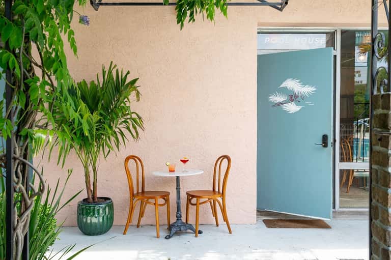 Small spa entrance with turquoise door, potted plants, and white bistro table setup