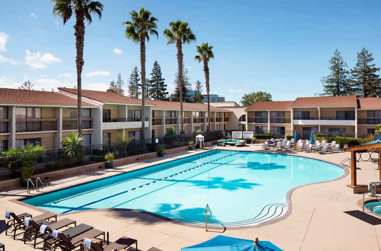 Resort pool with lane markings surrounded by palm trees and multi-story residential buildings