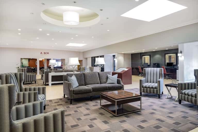 Spacious modern hotel lobby with neutral furnishings, skylight, multiple seating areas, and wayfinding signage