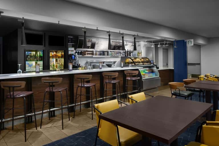 Casual cafe with counter seating, Starbucks signage, and yellow dining chairs