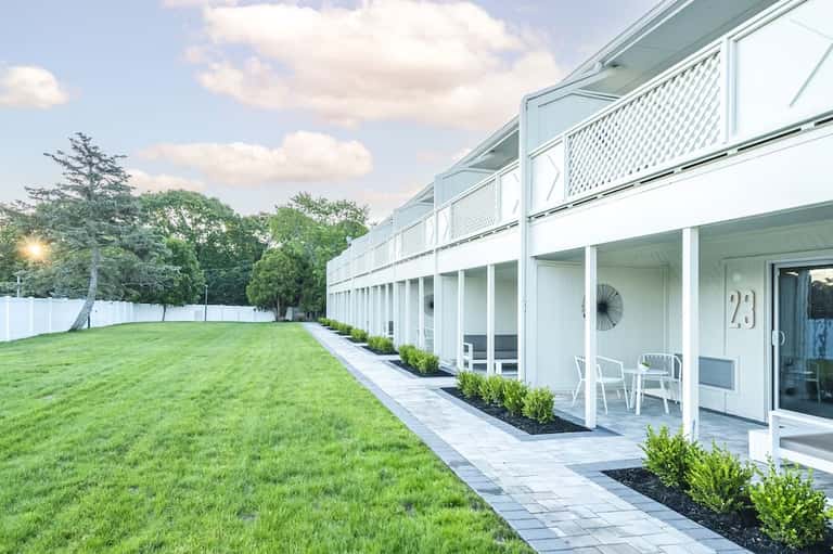 Modern residential building with waterfront walkway and manicured green lawn