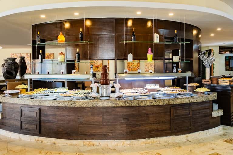 Elegant buffet counter with dark wood cabinetry, granite countertop, and hanging amber pendant lights