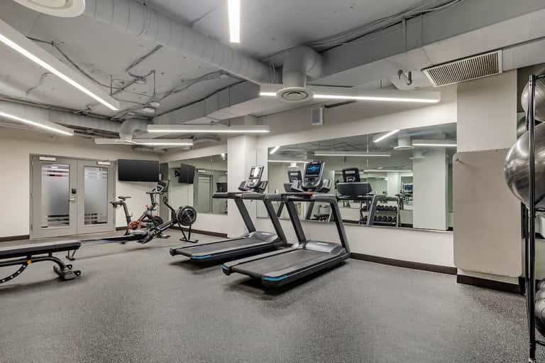 Fitness center with treadmills, exercise bikes, and gym equipment in well-lit space