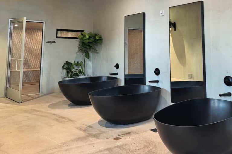 Luxury spa bathroom with freestanding black sonar bathtubs, mirrors, and modern minimalist design aesthetic