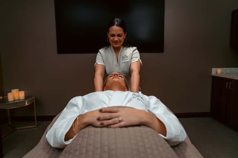 Spa therapist performing massage treatment on client in serene wellness room with candlelight